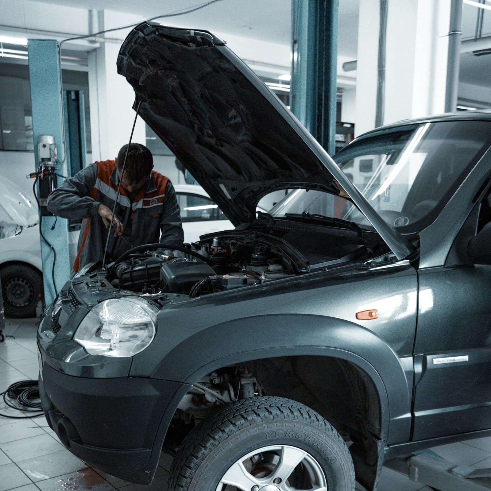 A Tolano's technician working on a vehicle on location, hood up, in the service bay